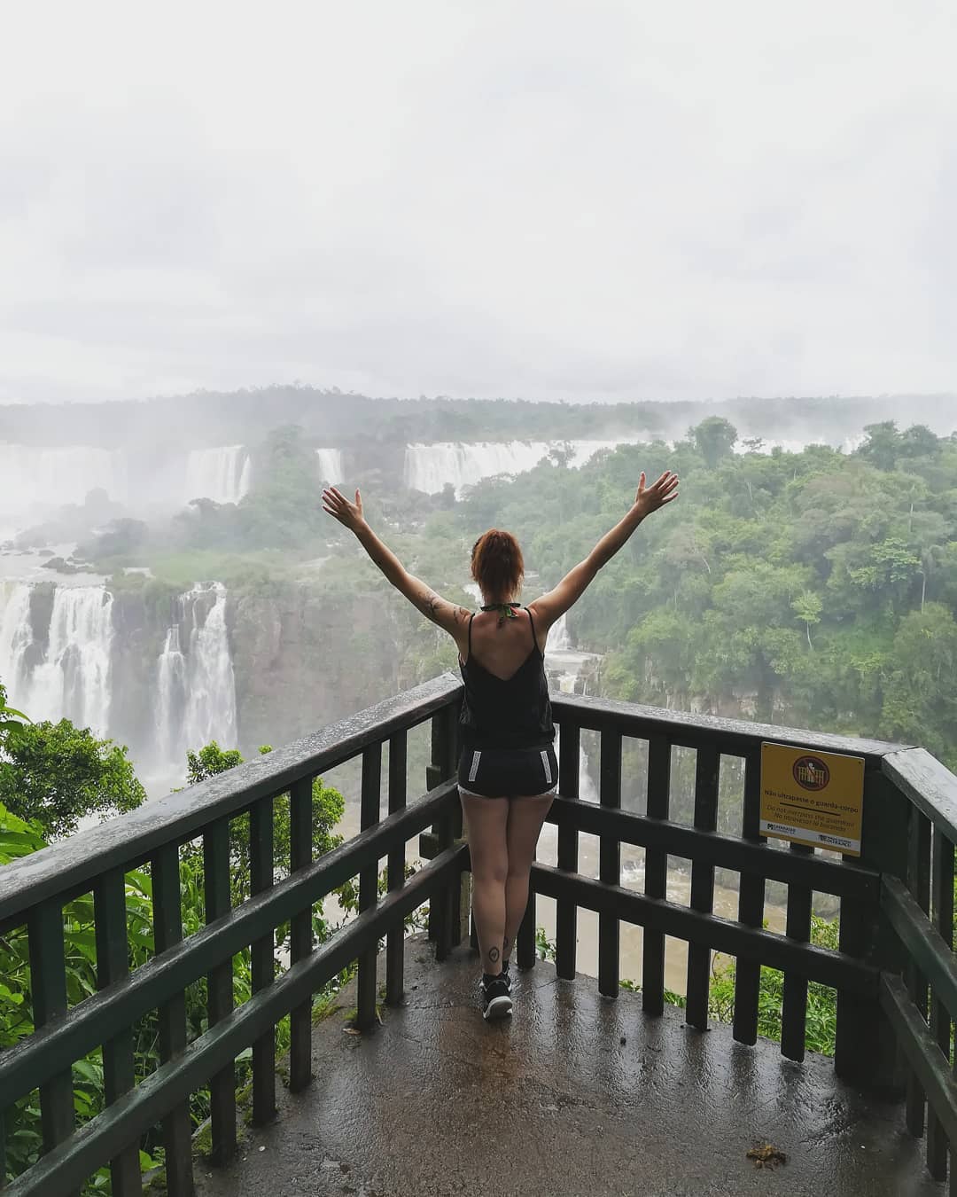 Ana Félix de braços abertos num miradouro sobre umas cataratas, no Brasil