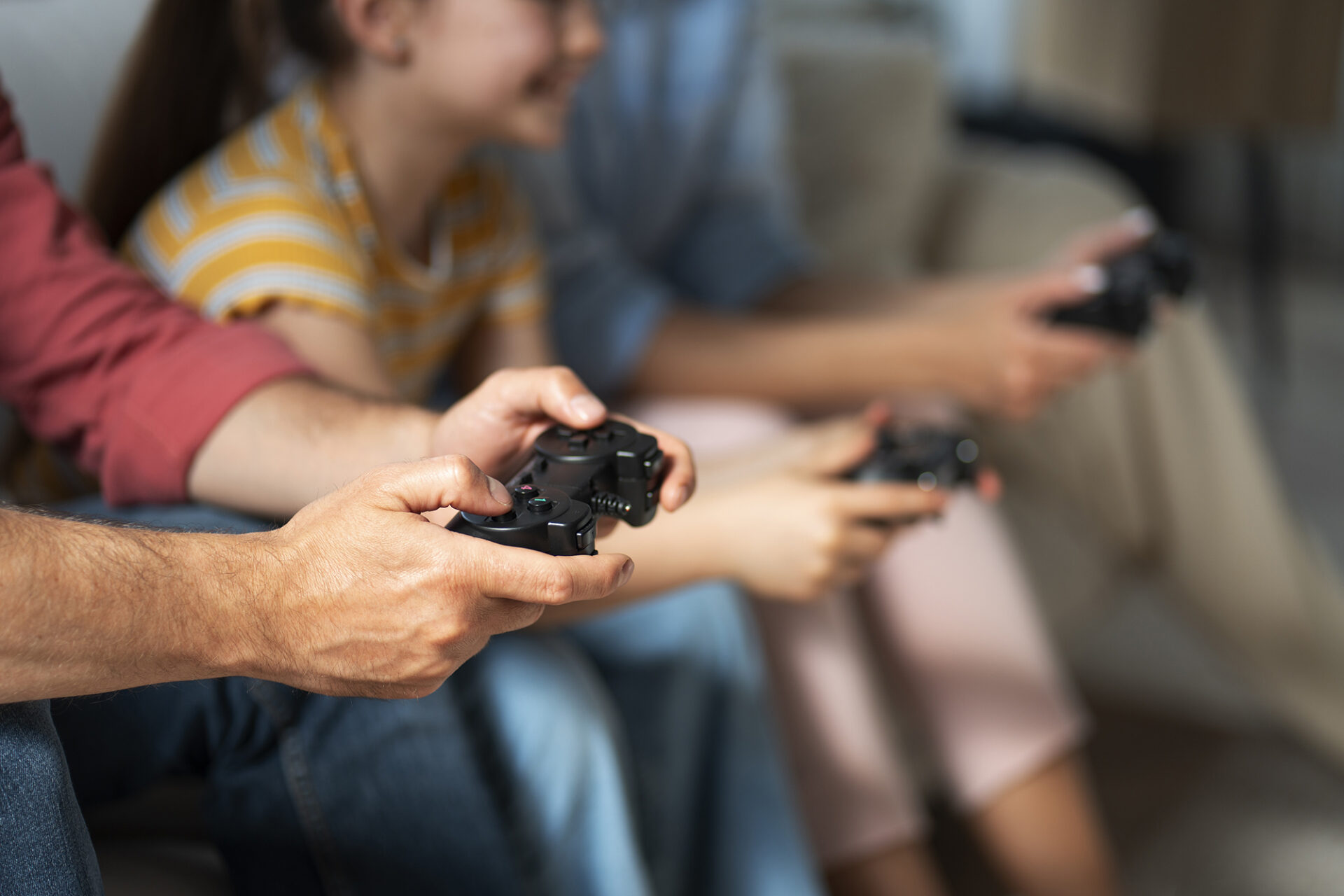 Pessoas sentadas no sofá a jogar videojogos com comandos na mão