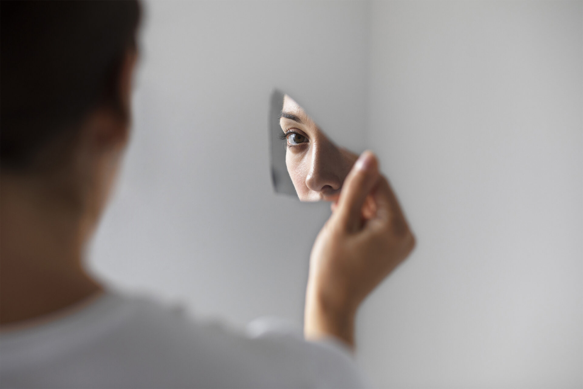 Pessoa a segurar um pequeno espelho que reflete o seu olhar