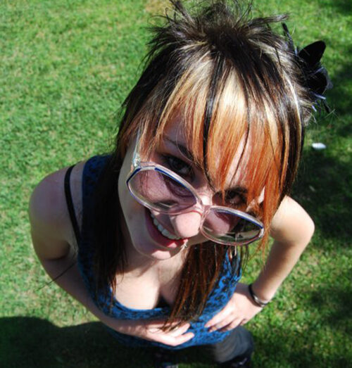 Ana Félix jovem, com óculos de sol e madeixas cor de laranja num jardim